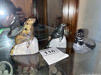 Three carvings displayed together: left seal carving in brown and black tones, middle black seal carving, right painted loon figurine with detailed black and white feathers.