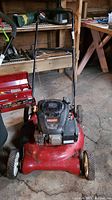 Front view of Craftsman lawnmower showing red deck, black engine with pull start and three visible wheels.