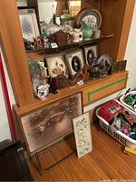 Wide shot of shelving unit displaying ceramic vases, decorative plates, banks, cutwork panels and framed art