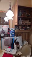 Overview photo showing many items in lot including boxes for Sunbeam heated throw, Vicks Sinus Inhaler, and Homedics foot massager along with visible cosmetics and razors on shelves.