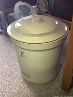 Full view of beige ceramic crock with lid in a room, showing size and shape.