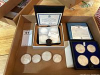 Overview showing two coin presentation cases and four loose coins