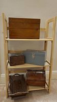 Front view of the wood shelf with wood boxes and a metal box arranged on it.