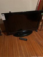 Full frontal view of Toshiba TV on wooden floor, remote visible in front