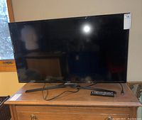 Full view of Samsung 40-inch LED television placed on a wooden dresser, showing front screen and stand.