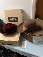 Two hats displayed side by side on a table with Helen Kaminski box and Banana Republic hat box visible