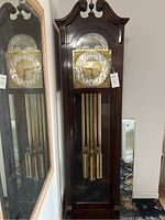 Full view of grandfather clock with adjacent mirror reflecting the clock and weights.