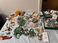 Full view of costume jewelry assortment including necklaces, earrings, brooches, and bracelets laid out on a surface.