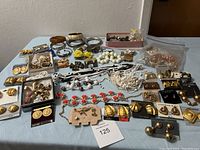 Overview photo of assorted vintage and costume jewelry including earrings, necklaces, and bracelets arranged on table.