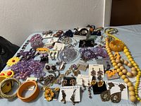 Photo showing full assortment of fashion jewelry including necklaces, bracelets, earrings, and rings arranged on a white table.