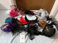 Wide shot of assortment of feather and fabric hair accessories including flower designs, feathered clips, and headbands in multiple colors