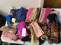 Overview photo of a large bundle of women's gloves of various colors and styles on a table, some with tags