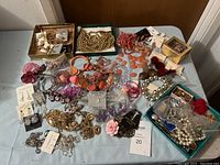Overhead view of assorted jewelry on table including necklaces, bracelets, earrings, and pins in various colors and styles.