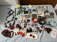 Full overview of all jewelry items spread on surface including bracelets, earrings, necklaces, and pins.