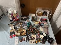 Large assortment of costume jewelry spread on table including beaded necklaces, earrings, bracelets, and keychains.