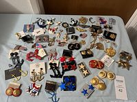 Top-down view of a collection of military and navy theme costume jewelry pieces arranged on a white surface.