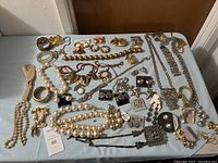 Image showing the full assortment of pearl and gold-tone costume jewelry items spread on a table.