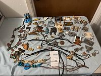Full view of all jewelry pieces laid out on a table, showing necklaces, earrings, pins, brooches, and bolo ties with southwestern designs.