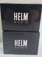 Two sealed black boxes of HELM AUDIO True Wireless In-Ear Headphones stacked vertically.