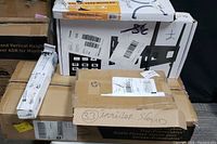 Five boxes stacked containing monitor stand, keyboard tray, TV wall mount with VESA kit, and mounting accessories.