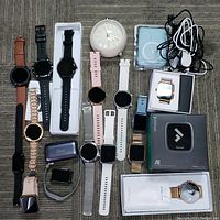 Full lot overview showing smart watches, earbuds, chargers, alarm clock