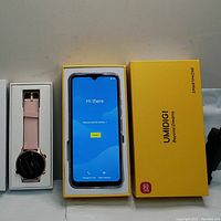 UMIDIGI Power 5 smartphone powered on in original yellow box beside smartwatch