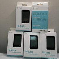 Front view of 5 boxed wireless bicycle computers SD-577C1 showing the front and back packaging with brand and model details.