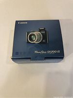 Closed box of Canon PowerShot SX200 IS digital camera with image of camera on front and branding.