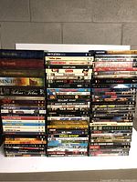 Photo showing a large selection of DVDs arranged standing upright with visible titles including box sets and individual movies.