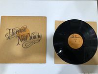 Front cover of the 'Harvest' vinyl album by Neil Young, showing the album title on a brown background.