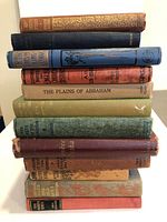 Stack of 12 old and rare books showing spines with titles, colors, and condition.