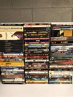 Photo showing large stack of assorted DVDs with various movie and series titles, including box sets and collections