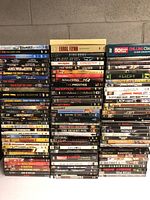 Stack of DVDs showing a wide variety of movie titles, genres including action, thriller, sci-fi and animation.