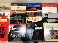 Front view of multiple vinyl soundtrack albums showing titles The Graduate, Oklahoma, Frank Chacksfield The King and I, Amadeus, The Godfather, Saturday Night Fever, and others.