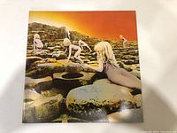 Front cover of Led Zeppelin's Houses Of The Holy vinyl album showing children climbing rocks under orange sky.