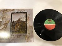 Front cover of Led Zeppelin IV album with iconic rustic frame and sticks artwork and vinyl disc showing colored Atlantic Records label side one.