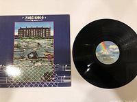 Front cover of The Who 'Hooligans' vinyl LP record alongside the black vinyl disc showing the disc's label with pastel rainbow and sky design.