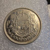 Reverse of 1955 Canadian fifty cent coin with Canadian coat of arms, denomination, and date.