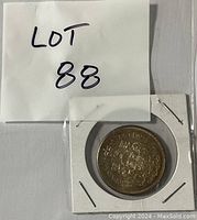 Image of reverse side showing the Canadian coat of arms and denomination, coin is stapled in a protective cardboard holder.