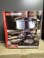 Box front showing 3 in 1 fondue set, including stainless steel pot on stand with burner, six small bowls, forks, and holder.