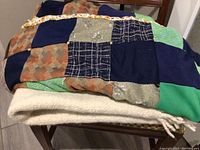 Quilted patchwork blanket with various colored fabric squares draped over a chair.