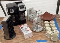 Photo taken showing the coffee machine, the vegetable peeler, the two coffee cup racks, multiple cups and saucers.