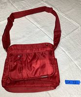 Front view of the red travel bag showing a pocket with snap button and Frommer's logo tag