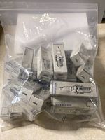 Multiple small boxes of new Honda NGK spark plugs visible inside a plastic bag.