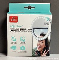 Front of the packaging showing Globe brand and Selfie Series Portable Selfie Light with usage icons for video chat, makeup, selfies, and photography. Shows circle of LEDs and dimmable intensity indication.