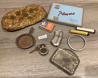 Full group photo of vintage items including art deco compact, cigarette tin, lock, miniature pan, lighter case, pill bottles, and coin purse