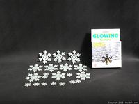 Photo of multiple white plastic snowflake ornaments spread out along with the box packaging labeled 'Glowing Snowflakes'