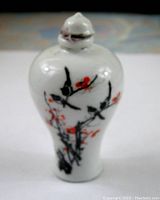 Front view of the vintage porcelain snuff bottle showing floral branch design with black and red accents on white porcelain.