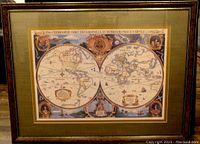 Framed decorative antique-style world map featuring two hemispheres and illustrated details.