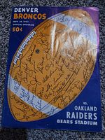 Front cover of the 1963 Denver Broncos official game program for the game vs Oakland Raiders, showing multiple signatures in pen across a football graphic and text with game details.